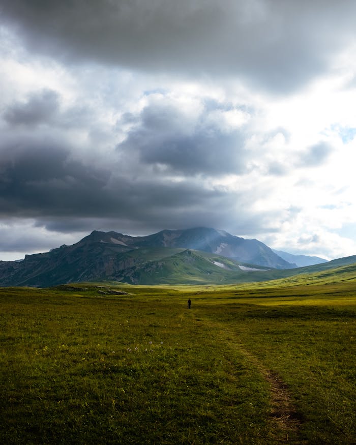 Expansive view of Adygea's mountainous landscape under a dramatic cloudy sky, ideal for nature lovers.
